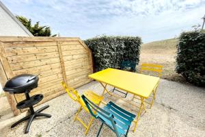 uma mesa amarela e cadeiras em frente a uma cerca em Maisonnette de charme - Refaite à neuf - Vue mer em Guidel