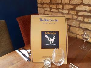 South Witham的住宿－The Blue Cow，一张桌子上摆着的标志,上面有两杯酒杯
