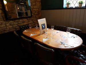 una mesa de madera en un restaurante con copas de vino en The Blue Cow, en South Witham