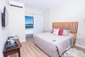 um quarto com uma cama, uma secretária e uma televisão em Hotel Villareal São Francisco do Sul em São Francisco do Sul