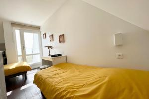 um quarto com uma cama amarela e uma janela em Maisonnette de charme - Refaite à neuf - Vue mer em Guidel