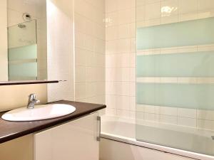 y baño blanco con lavabo y ducha. en Font -Romeu : Beau T4 avec parking, terrasse et vue, en Font-Romeu-Odeillo-Via