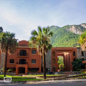 un edificio con palmeras frente a una montaña en Hotel Hacienda Cola del Caballo, en Santiago