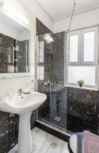 ein Badezimmer mit einem weißen Waschbecken und einer Dusche in der Unterkunft Sunny apartment on the 2nd floor in bohemian Psiri in Athens' historic center-In Vivo Apartments in Athen