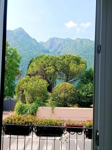 una ventana con vistas a los árboles y a las montañas en la casetta, en Abbadia Lariana