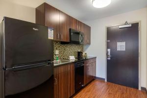 a kitchen with a black refrigerator and wooden cabinets at MainStay Suites St Louis Airport in Bridgeton
