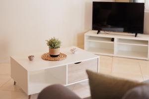 a living room with a white coffee table with a tv at Mythos Modern Loft in Dassia