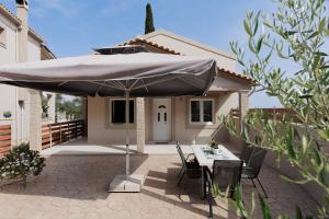 a patio with a table and an umbrella in front of a house at Mythos Modern Loft in Dassia