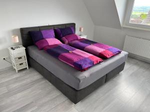 Elle comprend un grand lit avec des oreillers violets et violets. dans l'établissement Helle moderne Ferienwohnung, Nähe Koblenz am Rhein, à Weitersburg