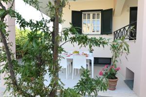 un patio con una mesa blanca, sillas y árboles en Casetta Primo Sole Apartments, en Policoro