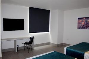 Cette chambre comprend un bureau et une table avec une chaise. dans l'établissement HOTEL RILUX Barrancabermeja, à Barrancabermeja