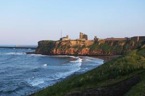 a castle on top of a cliff next to the ocean at Cozy Coastal Getaway in North Shields