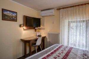 a bedroom with a desk and a bed and a television at Hotel Cecchin in Aosta