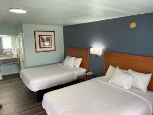 a hotel room with two beds with white sheets at Days Inn by Wyndham Pratt in Pratt