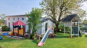 a yard with a playground with a slide and a house at Chalet im Spiel- und Obstgarten in Keidelheim