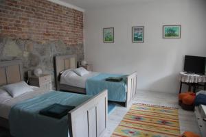 a bedroom with two beds and a brick wall at Mayday Cottage in Pócsmegyer