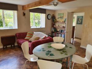 a living room with a table and a couch at Stable Cottage "The Unicorn Stable" in Yelverton