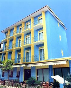 里米尼的住宿－HOTEL CLARA RIMINI 30m from the beach，蓝色和黄色的建筑,前面有椅子