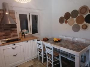 una cocina con armarios blancos y una isla con sillas en Beautiful house near the sea, en Kollimpithra