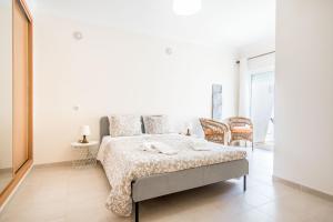 a white bedroom with a bed and chairs at #055 São José V by Home Holidays in Branqueira +87 photos
