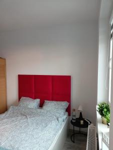 uma cama com uma cabeceira vermelha num quarto em Apartament z Jacuzzi i Sauna em Radom
