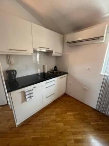 uma pequena cozinha com armários brancos e um lavatório em Casa David em Piran