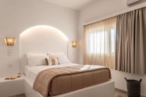 a white bedroom with a large bed and a window at Euphoria Suites and Spa in Kardamaina