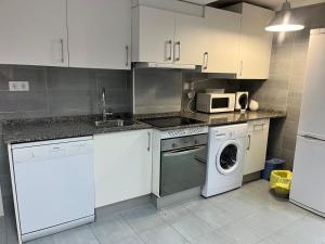 - une cuisine avec des placards blancs et un lave-linge/sèche-linge dans l'établissement Loft en Torrelavega, à Torrelavega