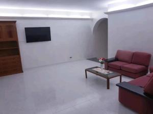 Una sala de estar con un sofá rojo y un televisor. en House with sea view/Casa con terrazzo vista mare, en Siderno Marina