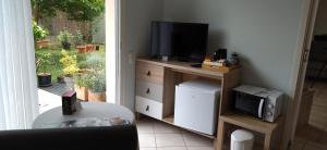 a living room with a television on a stand with a microwave at Fleurs de Cosmos in Albi