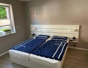 a bedroom with two beds with blue sheets and a window at Ankertau in Norden
