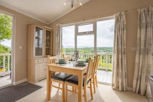 a dining room with a table and chairs and a large window at Tan Rallt Holiday Park & Spa in Abergele