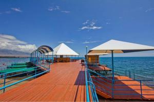 a wooden pier with chairs and umbrellas on the water at Квартира в Радуга WEST in Koshkolʼ