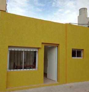 a yellow building with a white door and a window at CENTENO CASI 9 DE JULIO in Santa Rosa