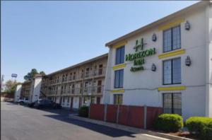 a large white building with a hotel sign on it at Horizon Inn Norcross in Norcross