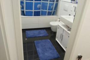 y baño con lavabo, aseo y alfombras azules. en Zimmer mit eigenem Bad in Märchenstadt!, en Heidelberg