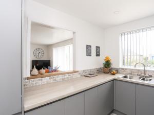 a kitchen with white cabinets and a large mirror at 31 Beach Road in Porthmadog +28 photos