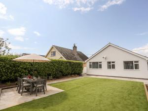 a garden with a table and chairs and an umbrella at 31 Beach Road in Porthmadog