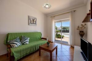 een woonkamer met een groene bank en een glazen schuifdeur bij Casa Bege T1 in Burgau