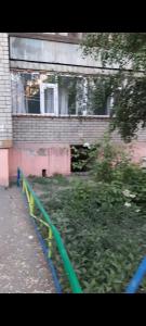 a green fence in front of a building at Уютная квартира in Semey