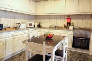 a kitchen with white cabinets and a table and chairs at Casa da Rocha - Alojamento Local in Vila Nova de Foz Coa +14 photos
