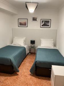 Habitación con 2 camas y mesa con lámpara. en Casa da Rocha - Alojamento Local en Vila Nova de Foz Cõa