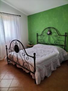 a bedroom with a bed with a green wall at Pergole in Realmonte
