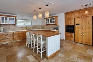 a kitchen with wooden cabinets and a island with bar stools at אחוזת אלטה גלילאה - לנפוש בארץ להרגיש בחו"ל in Yesud HaMa‘ala