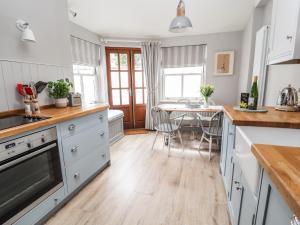 cocina con armarios blancos y suelo de madera en Bay Tree Cottage en Beaumaris
