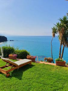 a bench sitting on the grass near the ocean at Casa Guido in Cittadella del Capo