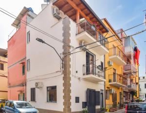 a white building with balconies and cars parked on a street at AMUNI' Apartments in Trabia