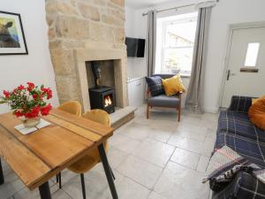 ein Wohnzimmer mit Tisch und Kamin in der Unterkunft Old Stone Cottage in Harrogate