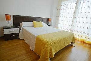 sypialnia z łóżkiem przykrytym żółtym kocem w obiekcie Apartamento con piscina próximo a Sanxenxo w mieście Sanxenxo