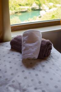 Una toalla sentada en una cama frente a una ventana en Apartman Dva mosta en Mostar